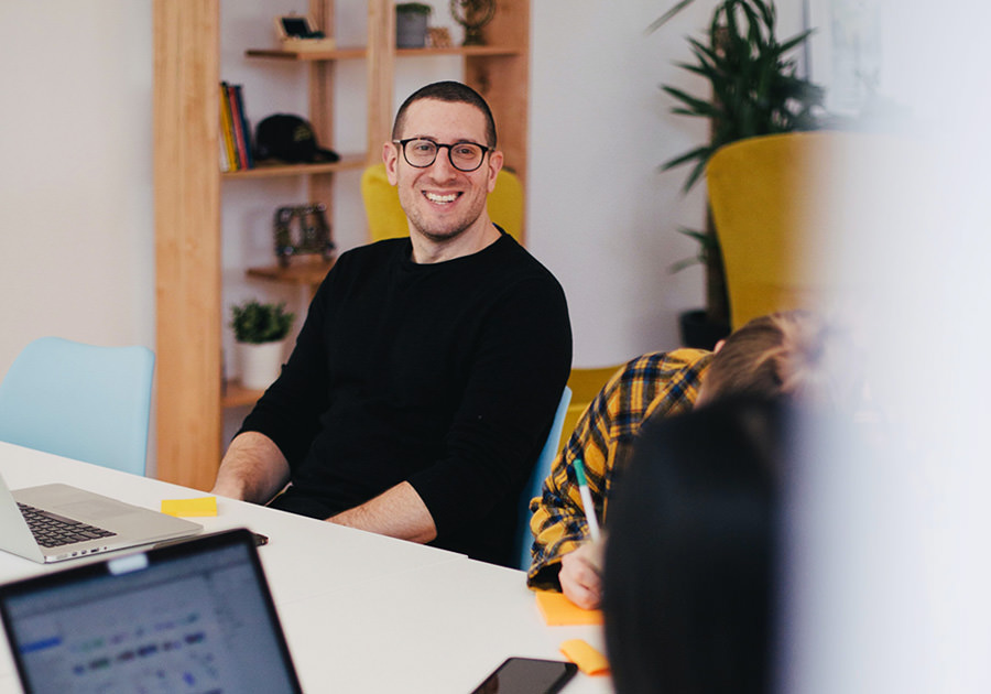 Man in black sweater smiling during a meeting in a modern office. Man in black sweater smiling during a meeting in a modern office.